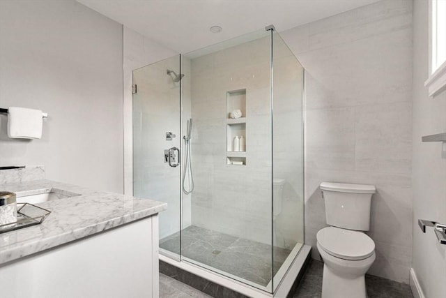 bathroom featuring toilet, vanity, and a shower with shower door