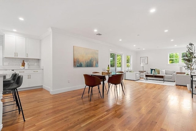 dining room with light hardwood / wood-style flooring and crown molding