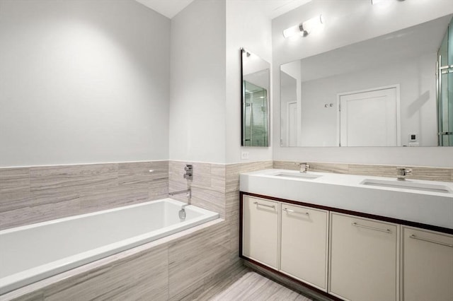 bathroom featuring vanity and a relaxing tiled tub