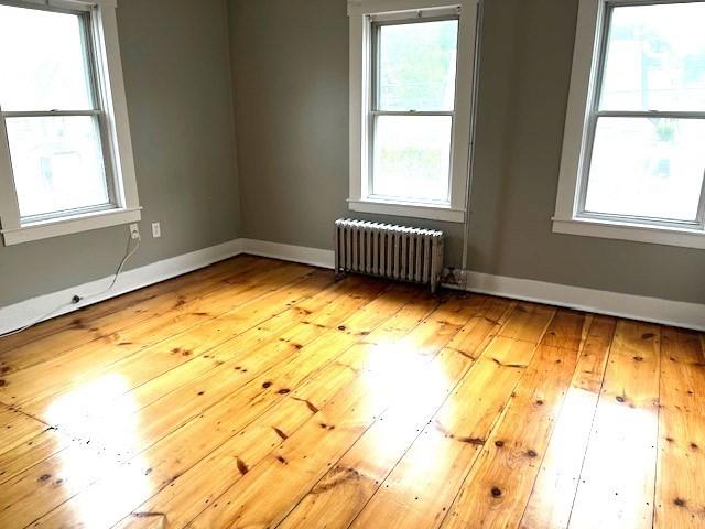 129 3rd St, Lowell, MA 01850 - spare room featuring radiator heating unit, hardwood / wood-style floors, baseboards, and plenty of natural light