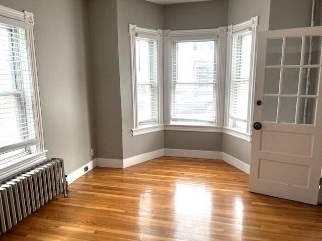 129 3rd St, Lowell, MA 01850 - unfurnished room featuring radiator heating unit, baseboards, light wood finished floors, and plenty of natural light