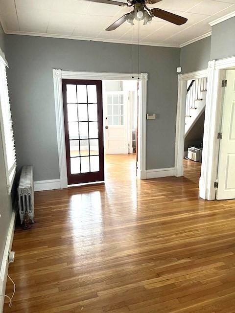 129 3rd St, Lowell, MA 01850 - unfurnished room featuring radiator, crown molding, a ceiling fan, wood finished floors, and stairs