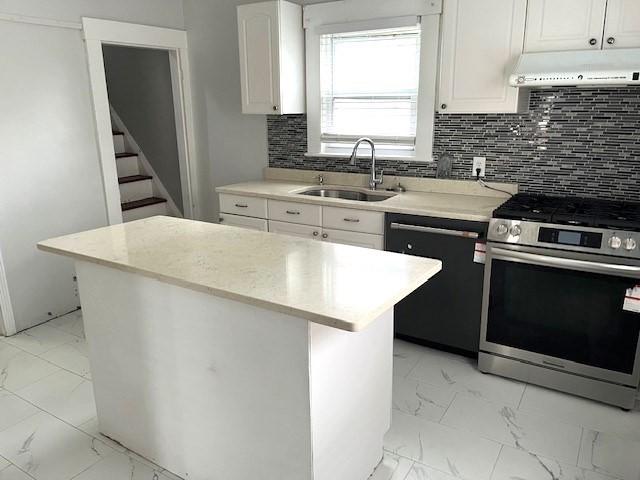 129 3rd St, Lowell, MA 01850 - kitchen with stainless steel gas stove, dishwasher, light marble finish floors, a sink, and extractor fan