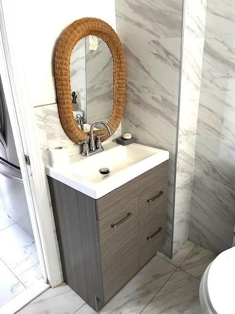 129 3rd St, Lowell, MA 01850 - half bath featuring vanity, marble finish floors, toilet, and tile walls