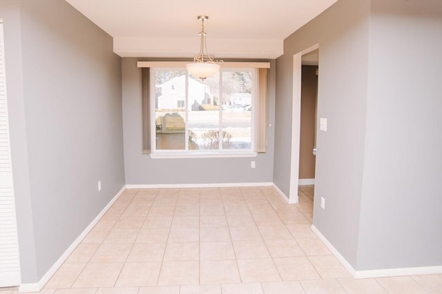 unfurnished dining area with light tile patterned floors and baseboards