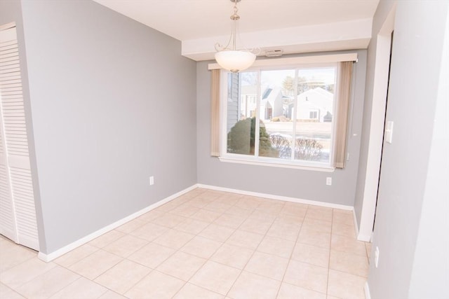 unfurnished dining area with light tile patterned floors and baseboards