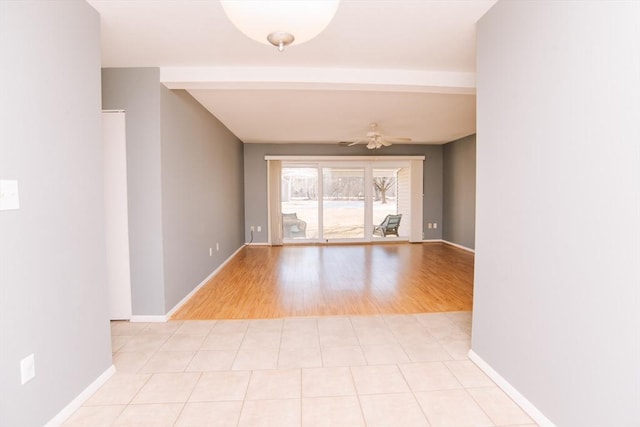 empty room with ceiling fan, light tile patterned floors, beam ceiling, and baseboards