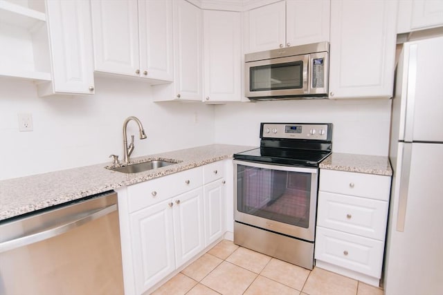 kitchen with light tile patterned floors, appliances with stainless steel finishes, a sink, and white cabinets