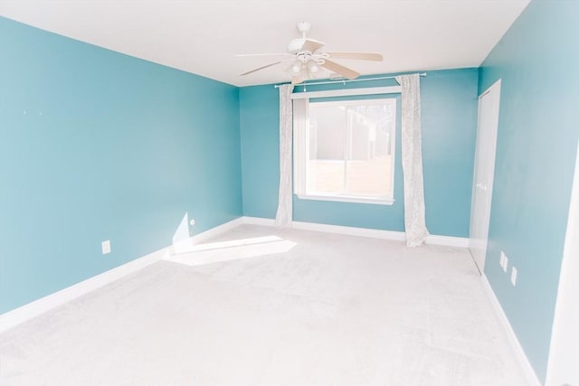 carpeted spare room with baseboards and a ceiling fan