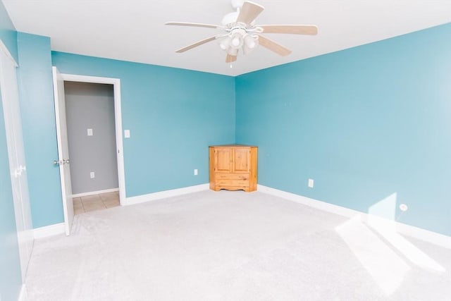 carpeted empty room with ceiling fan and baseboards