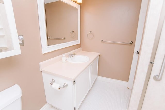 bathroom featuring toilet, tile patterned flooring, baseboards, and vanity