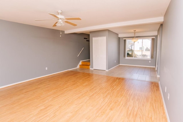 unfurnished room with light wood-style floors, ceiling fan, stairway, and baseboards