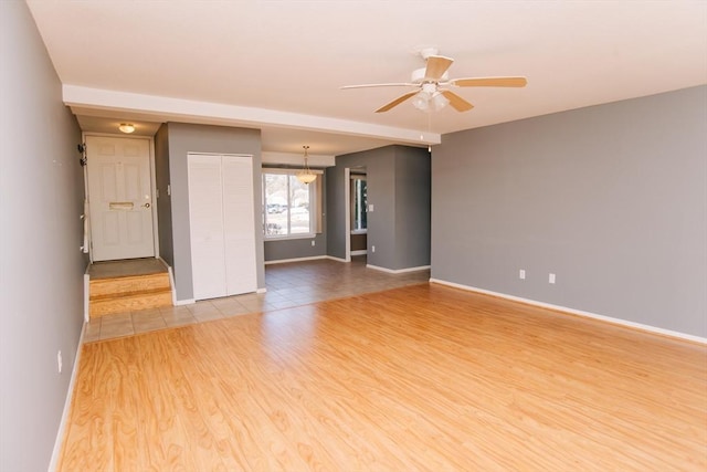 unfurnished room with baseboards, light wood-style flooring, and a ceiling fan