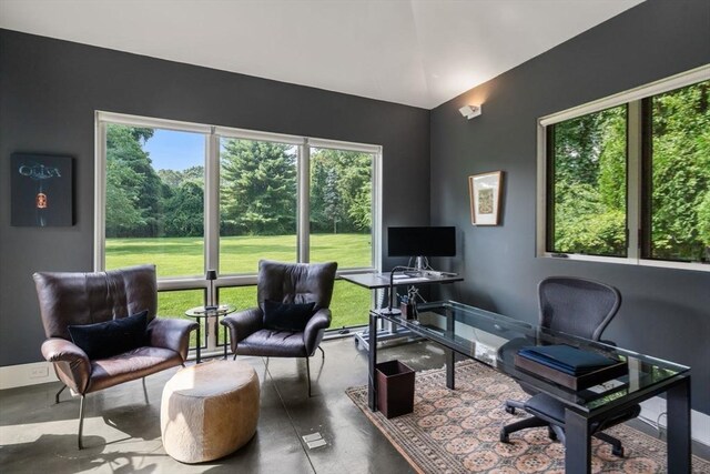 home office featuring lofted ceiling and finished concrete flooring