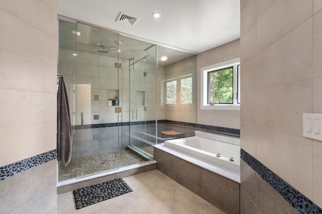 full bathroom with visible vents, a garden tub, tile walls, and a stall shower