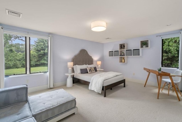 carpeted bedroom featuring visible vents, multiple windows, and baseboards