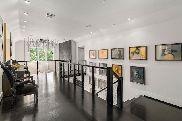 corridor with lofted ceiling, an upstairs landing, wood finished floors, and visible vents