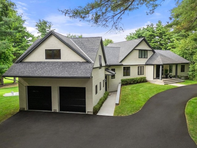 view of front of house with a garage, driveway, a shingled roof, and a front lawn