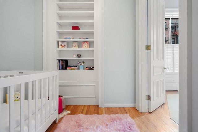 bedroom with wood finished floors and a crib