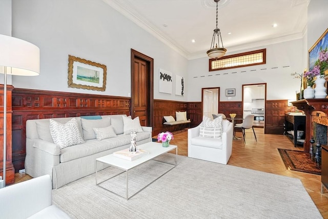 living area with wainscoting, ornamental molding, recessed lighting, and a towering ceiling