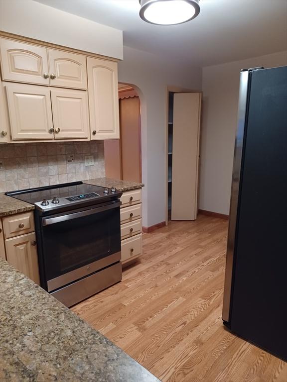 822 N Eastern Ave, Fall River, MA 02720 - kitchen with stainless steel appliances, arched walkways, light wood-style floors, decorative backsplash, and light stone countertops