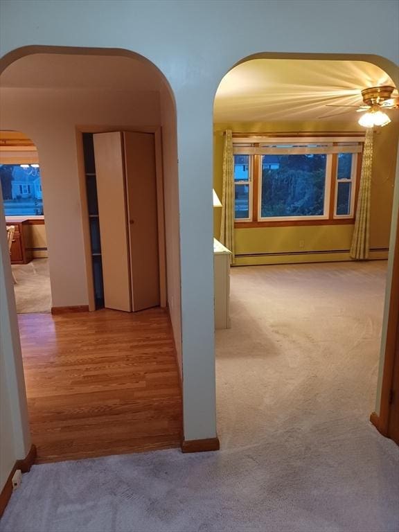 822 N Eastern Ave, Fall River, MA 02720 - hallway featuring arched walkways, a baseboard heating unit, light colored carpet, and baseboards
