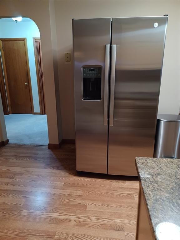 822 N Eastern Ave, Fall River, MA 02720 - kitchen featuring stainless steel refrigerator with ice dispenser, light wood-style floors, baseboards, light stone counters, and arched walkways