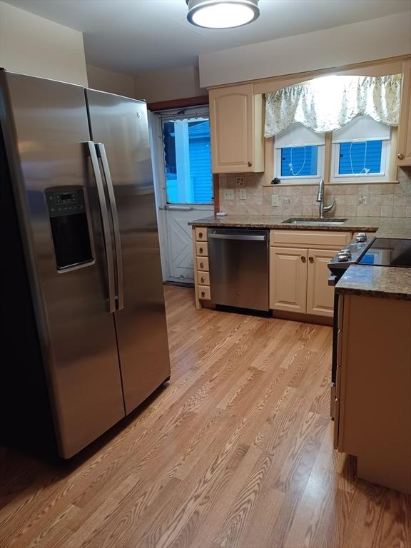 822 N Eastern Ave, Fall River, MA 02720 - kitchen with stainless steel appliances, light wood-style floors, a sink, and decorative backsplash