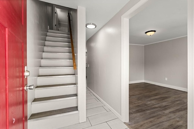 stairway featuring baseboards, ornamental molding, and wood finished floors