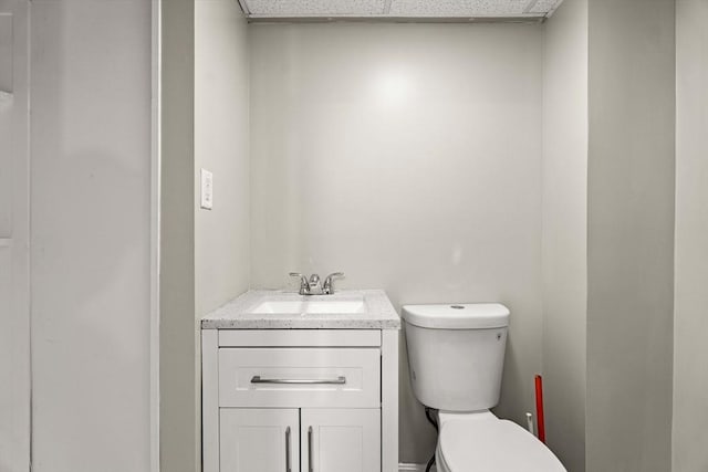bathroom featuring vanity, a drop ceiling, and toilet