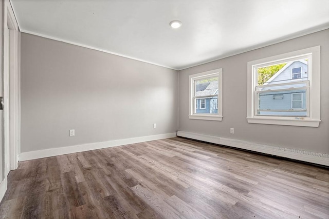 unfurnished room with baseboards, a baseboard heating unit, and wood finished floors