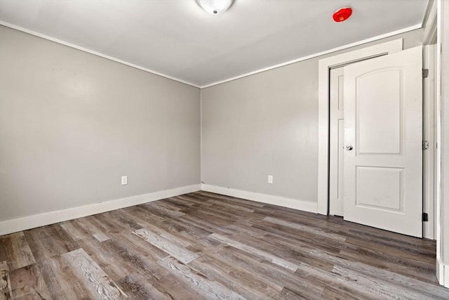 unfurnished room featuring crown molding, baseboards, and wood finished floors