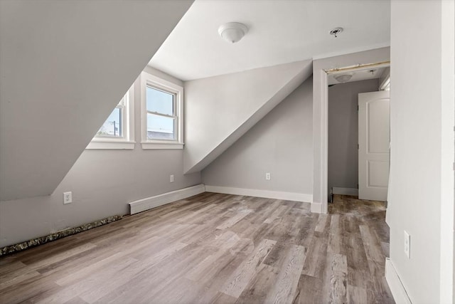 additional living space featuring baseboards and wood finished floors