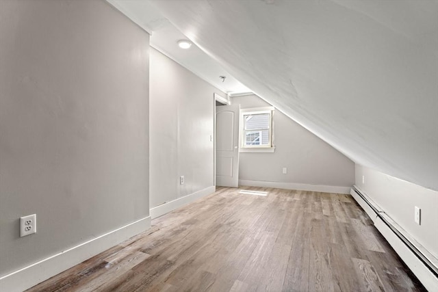 additional living space with baseboards, a baseboard radiator, wood finished floors, and lofted ceiling