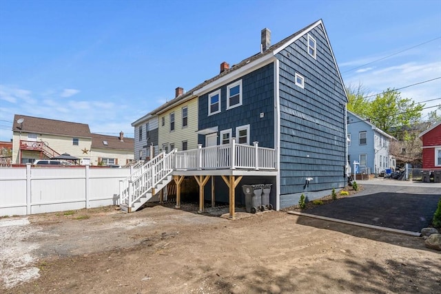 back of property featuring stairway, a deck, fence, and a chimney