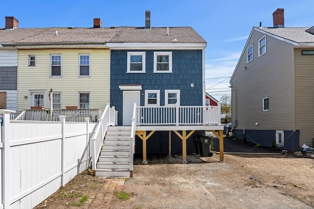 rear view of house with a deck, fence, a chimney, and stairs
