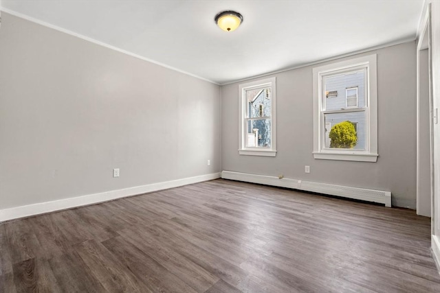 spare room featuring crown molding, baseboards, a baseboard radiator, and dark wood finished floors