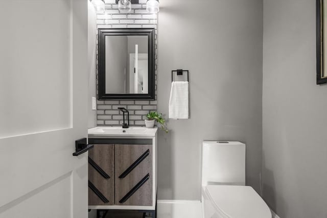 bathroom featuring toilet, vanity, and tasteful backsplash