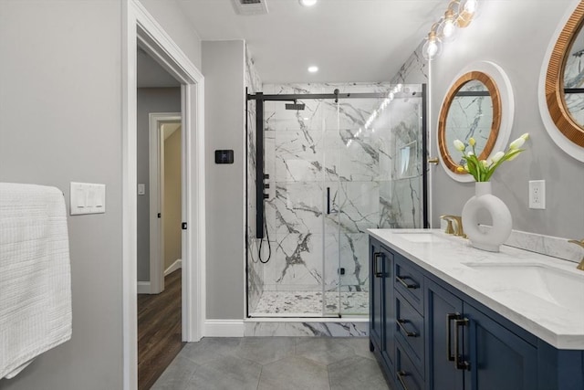 bathroom with recessed lighting, a marble finish shower, double vanity, and baseboards