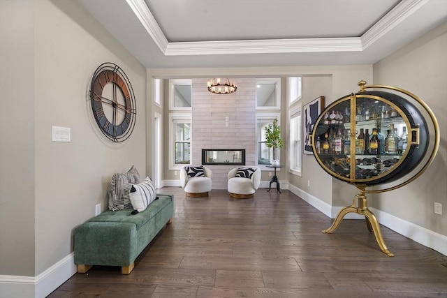 sitting room with a tray ceiling, hardwood / wood-style floors, crown molding, and baseboards