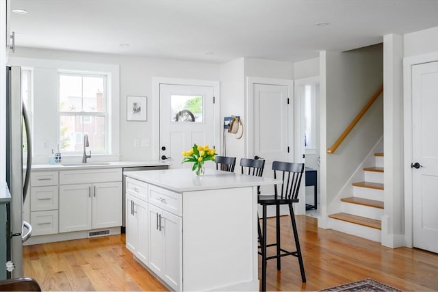 6 Macdonald Ter Unit E, Scituate, MA 02066 - kitchen featuring a sink, a breakfast bar area, freestanding refrigerator, light wood-style flooring, and white cabinets