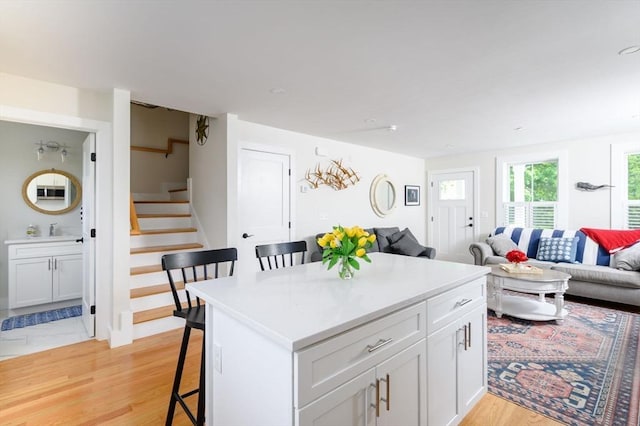 6 Macdonald Ter Unit E, Scituate, MA 02066 - kitchen featuring a kitchen bar, open floor plan, light wood-style flooring, white cabinets, and a center island