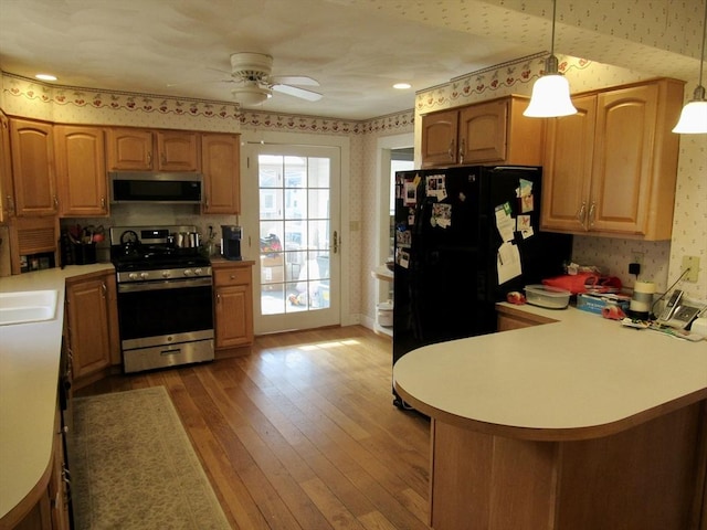 kitchen featuring wallpapered walls, stainless steel appliances, ceiling fan, and wood-type flooring