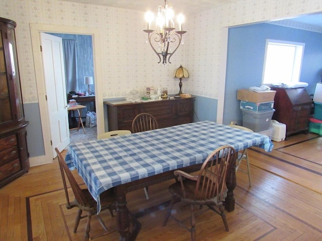 dining room featuring wallpapered walls, wood finished floors, and a chandelier