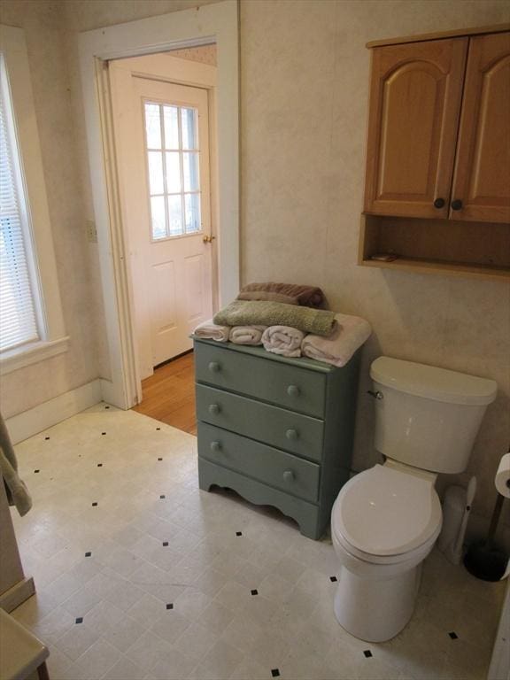 bathroom with a wealth of natural light, toilet, and tile patterned floors