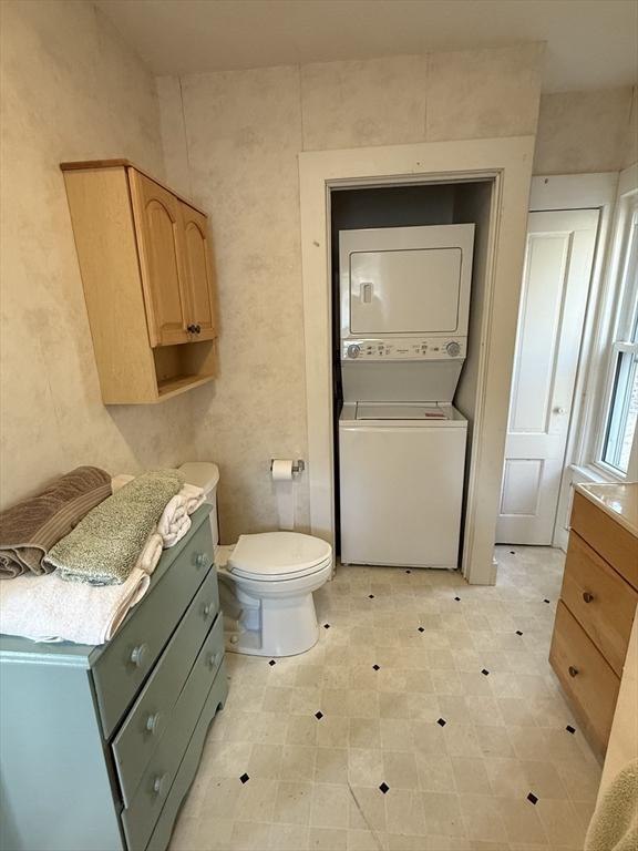 bathroom with stacked washer and dryer and toilet