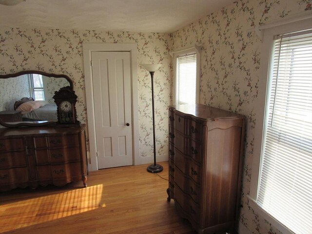 bedroom featuring wallpapered walls and wood finished floors