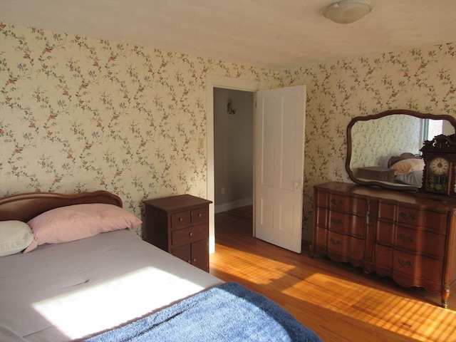 bedroom featuring wood finished floors and wallpapered walls