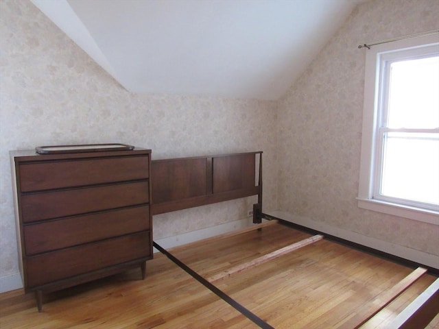 interior space with baseboards, lofted ceiling, light wood-style floors, and wallpapered walls