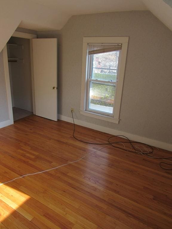 bonus room with light wood-style floors and vaulted ceiling